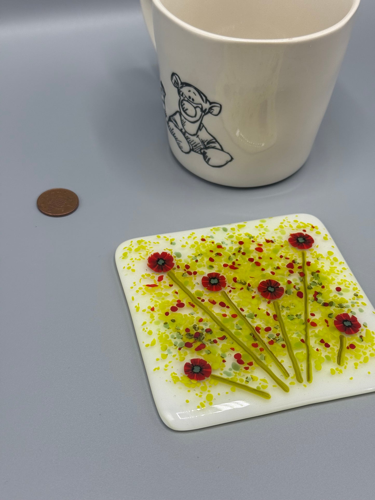 Decorative plate with floral design next to a mug on a gray surface
