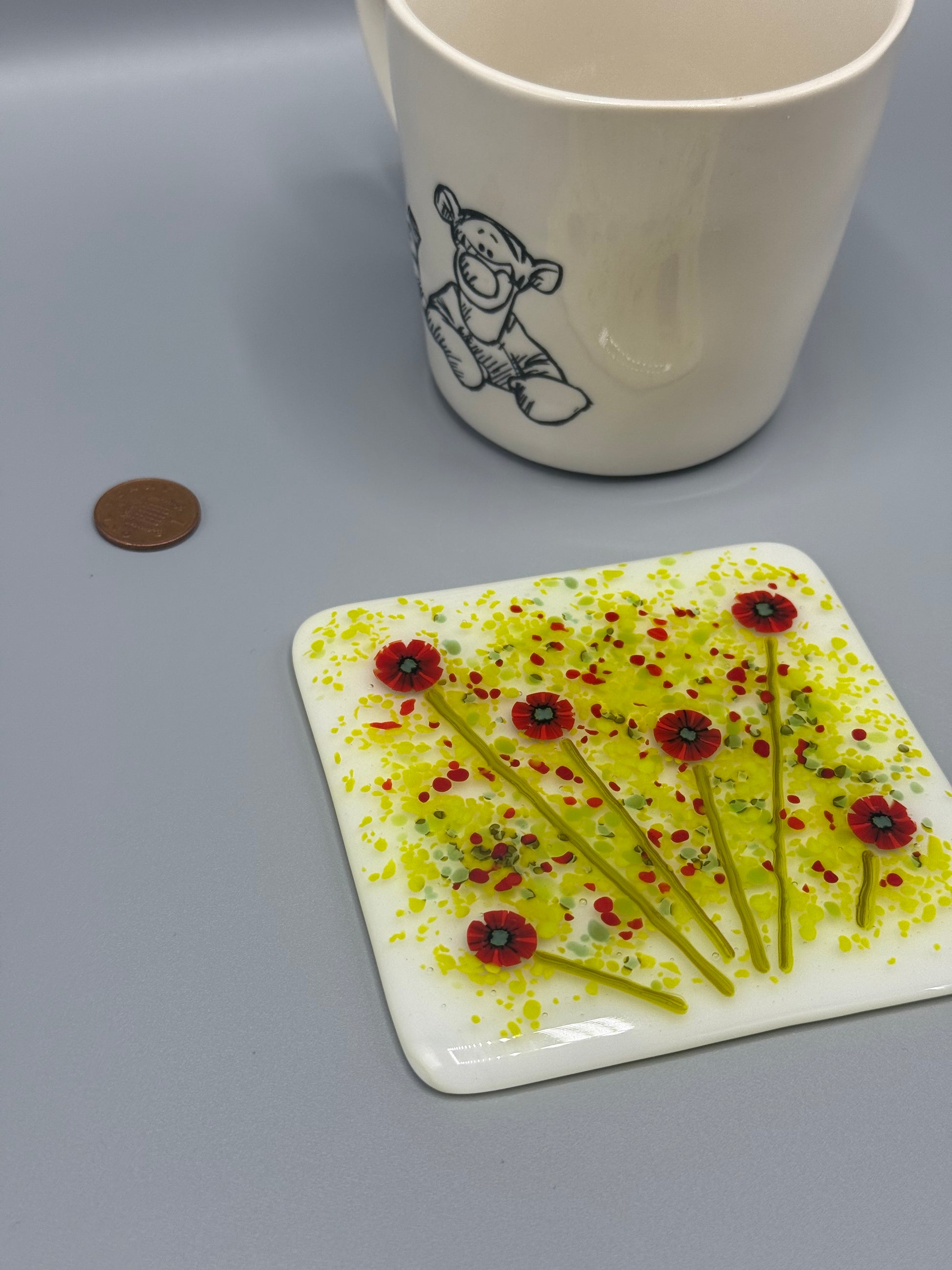 Decorative plate with floral design next to a mug on a gray surface