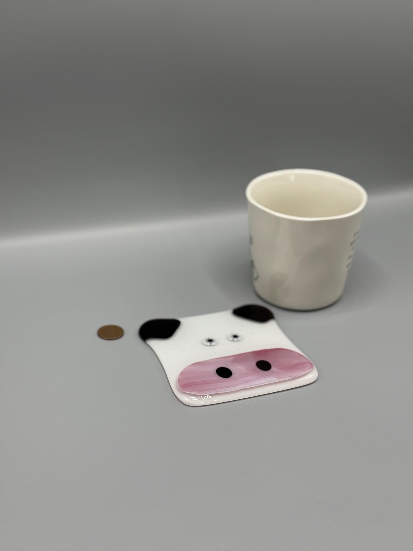 Coaster with panda design next to a cup on a gray background