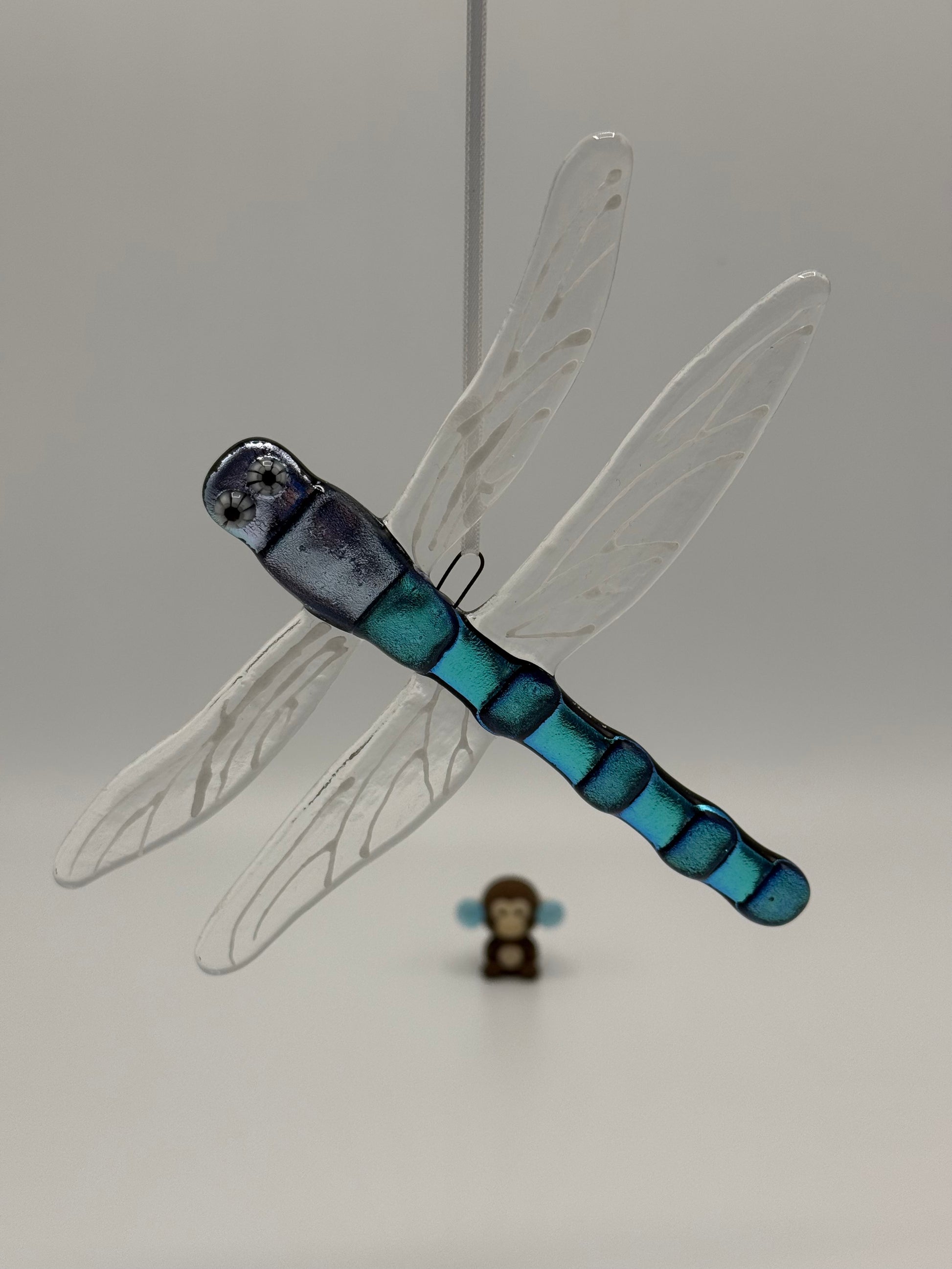 Model of a dragonfly with blue and black body on a plain background