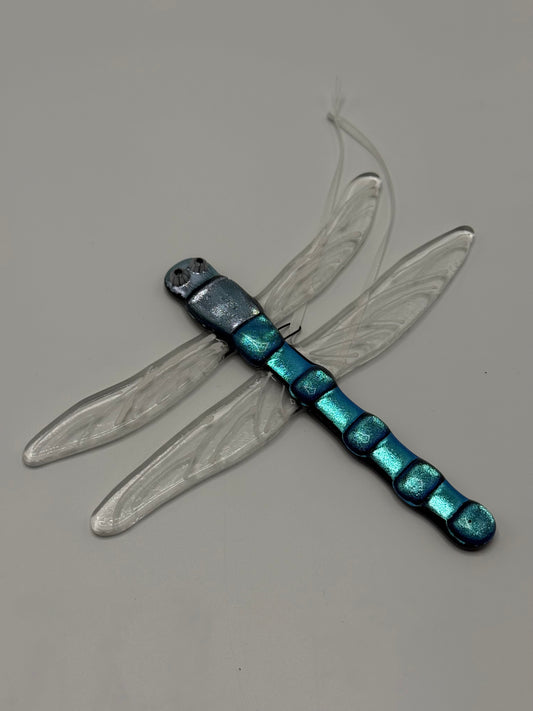 Decorative dragonfly with metallic blue body and clear wings on a gray background